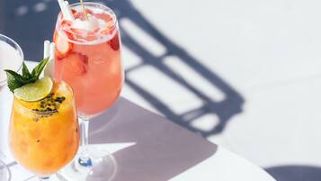 Due cocktail su un tavolo bianco, con l'ombra di una struttura.