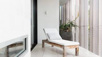 Relax in a serene lounge area with a comfortable chair and lush greenery.