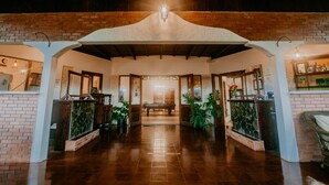 A lobby with a high ceiling, brick walls, and a central bench. - The Golden Frog Inn (El Valle de Anton)