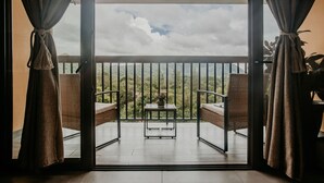 A balcony with wicker furniture and a small table, offering a view of a mountainous landscape. - The Golden Frog Inn (El Valle de Anton)