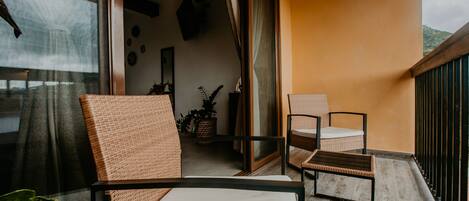 A balcony with wicker furniture, a potted plant, and a view of the outdoors.