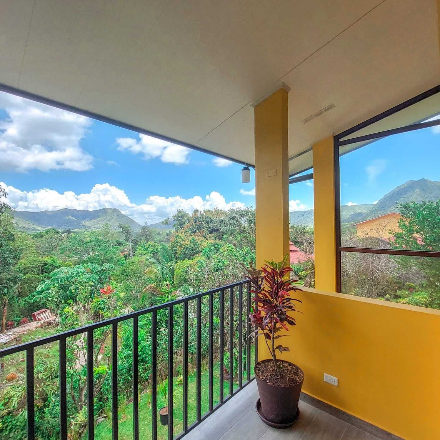 Uma varanda com vista para uma paisagem verdejante e montanhas.