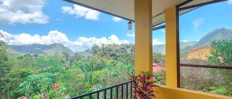 A balcony with a view of a lush green landscape and mountains.