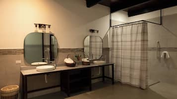 A modern bathroom with a vanity, two sinks, a shower, and a mirror.