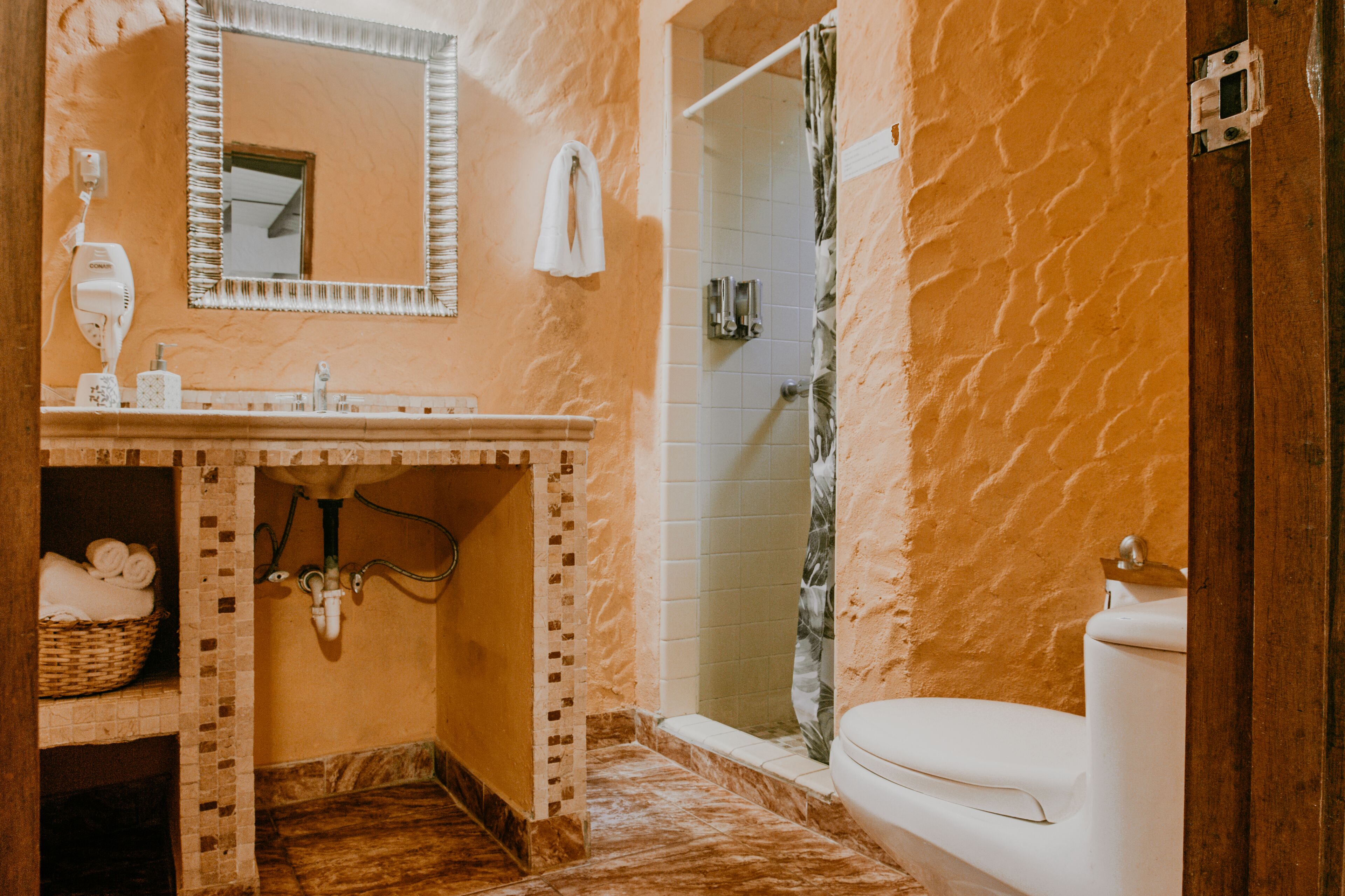 A bathroom with a marble floor, a sink, a toilet, a shower, and a mirror.