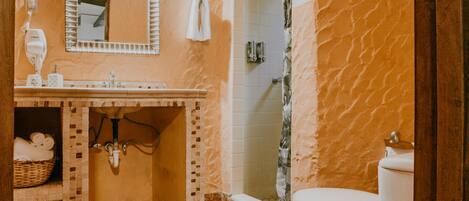 A bathroom with a marble floor, a sink, a toilet, a shower, and a mirror.