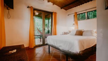 A bedroom with a bed, a small table, and a window with curtains.