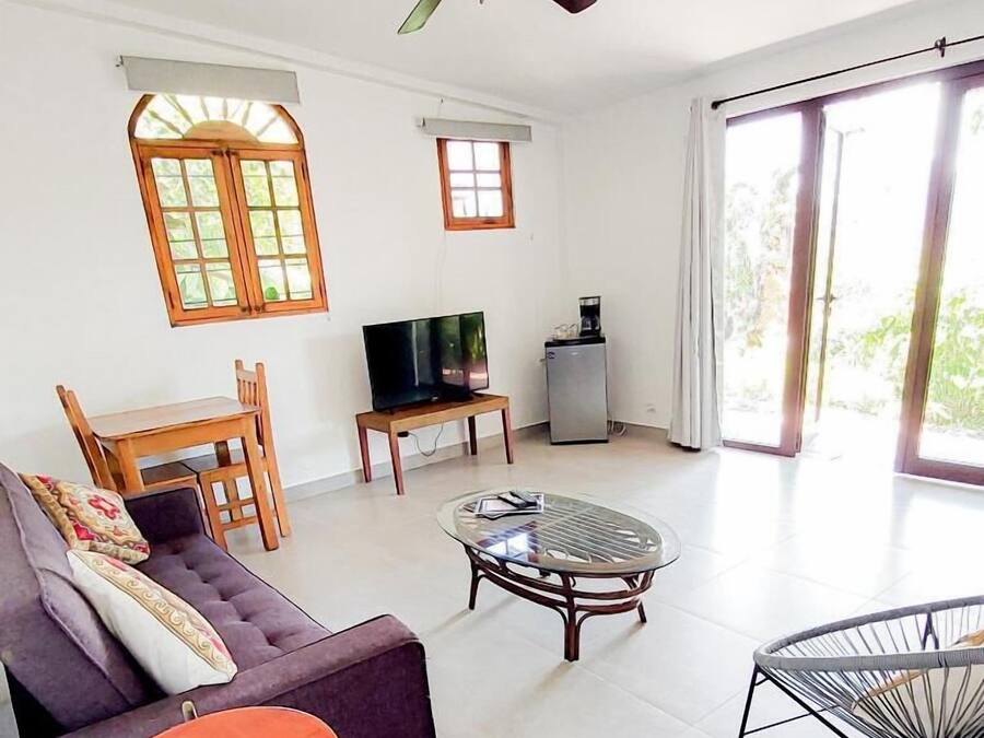 A living room with a sofa, a coffee table, a TV, and a ceiling fan.