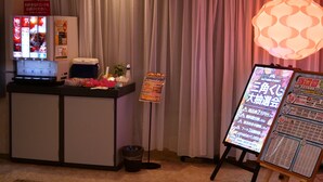 A reception desk with a Coca-Cola vending machine, a small refrigerator, and a trash bin. There is a signboard with event information and a decorative light fixture. - HOTEL DRESSY -Adults Only (Himeji)