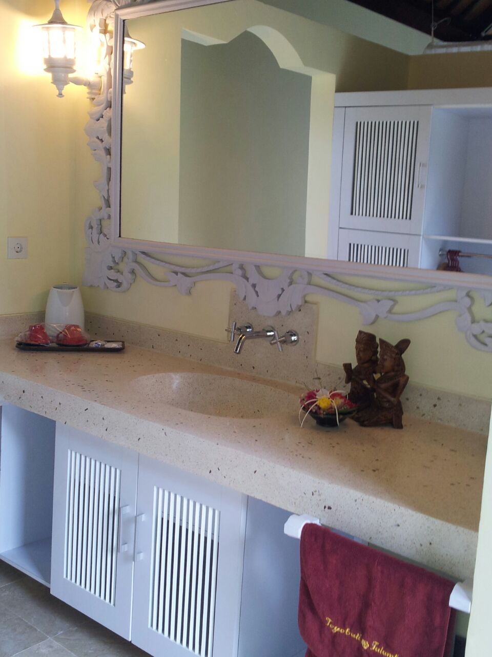 A bathroom with a large mirror, a sink, a towel rack, and a decorative item on the counter.