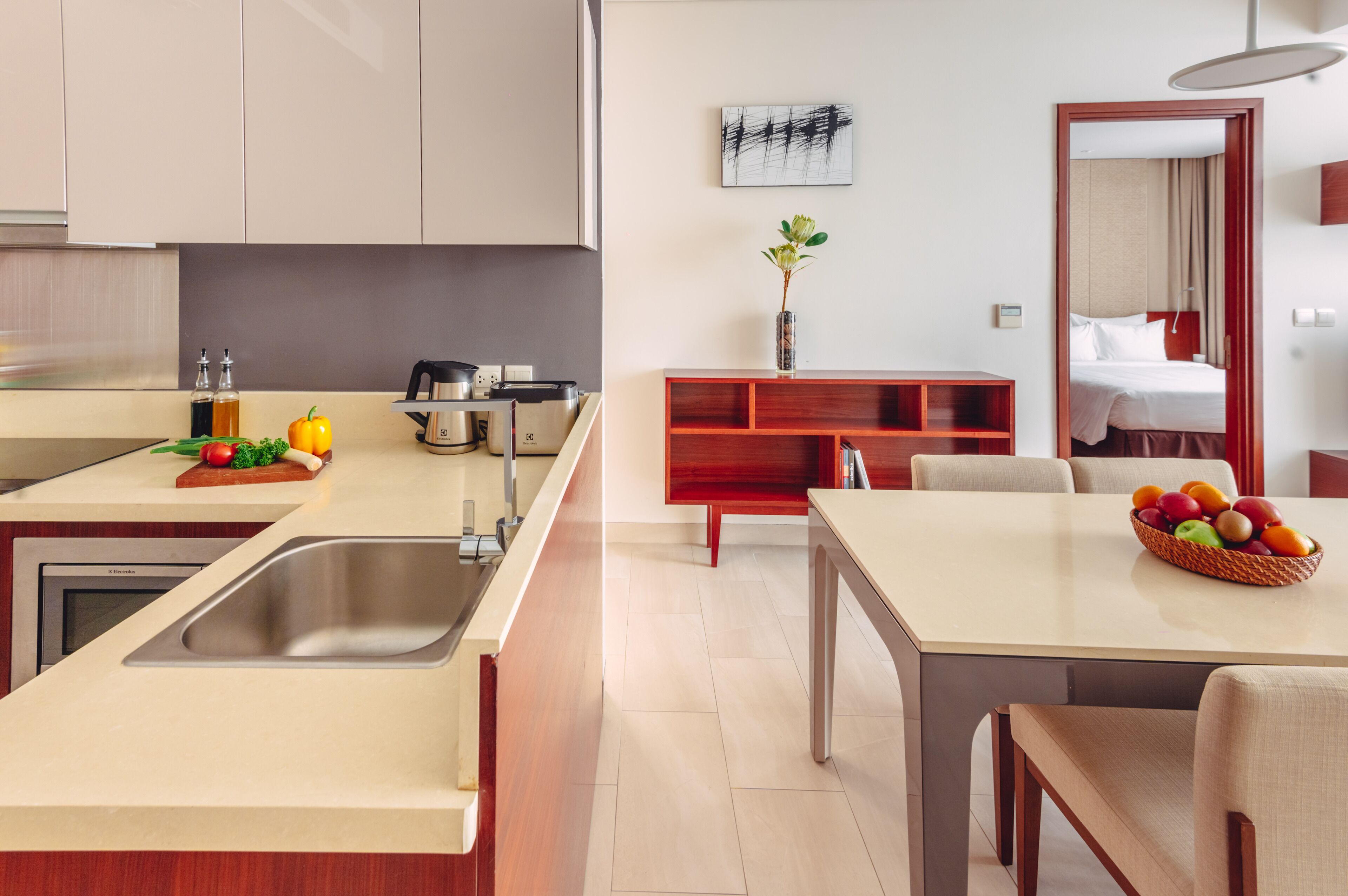 Une cuisine moderne dotée d’un évier intégré, d’un coin repas avec une table et des chaises, et d’une petite plante accrochée au mur.