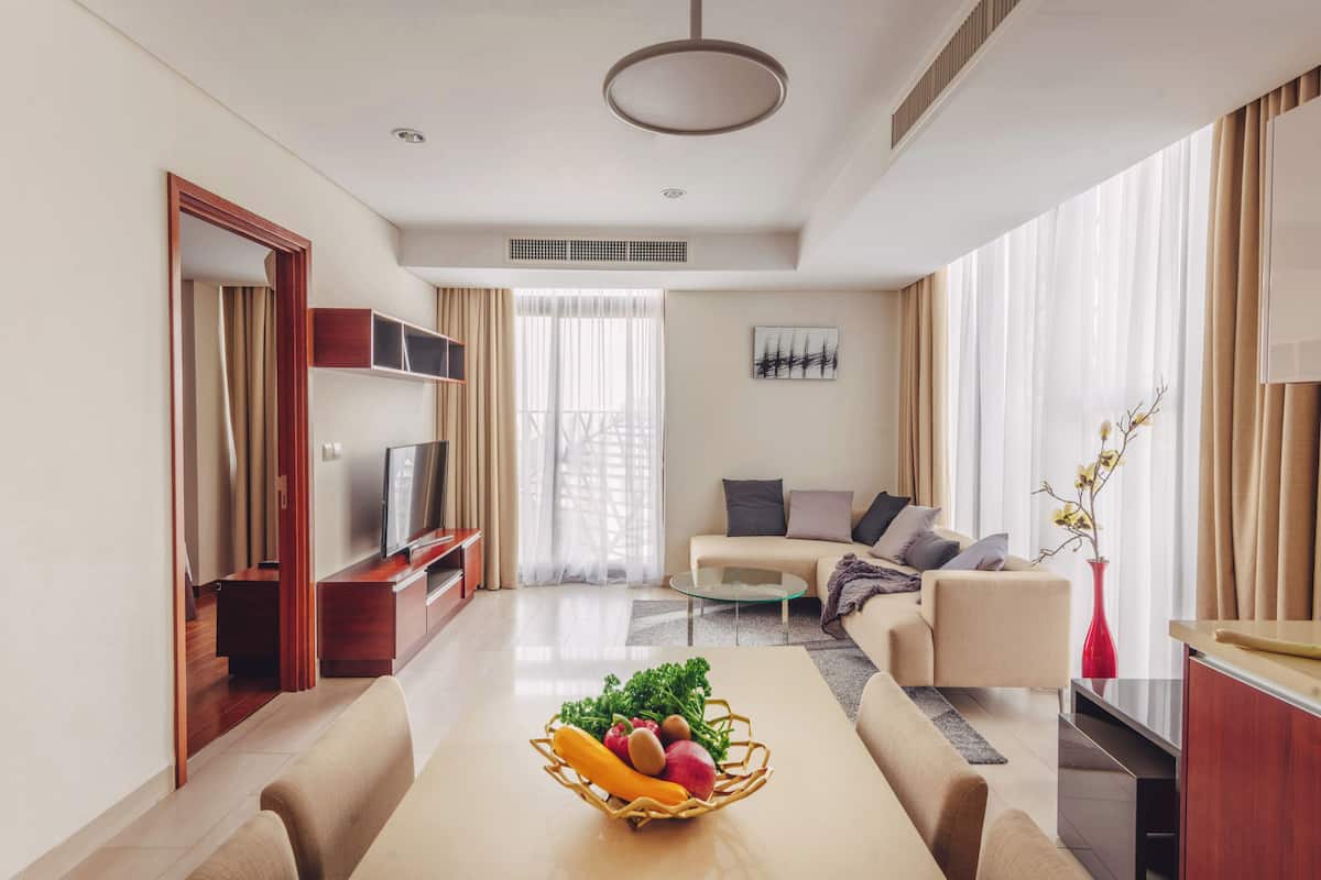 Een moderne woonkamer met een bank, televisie en een fruitmand op een salontafel.