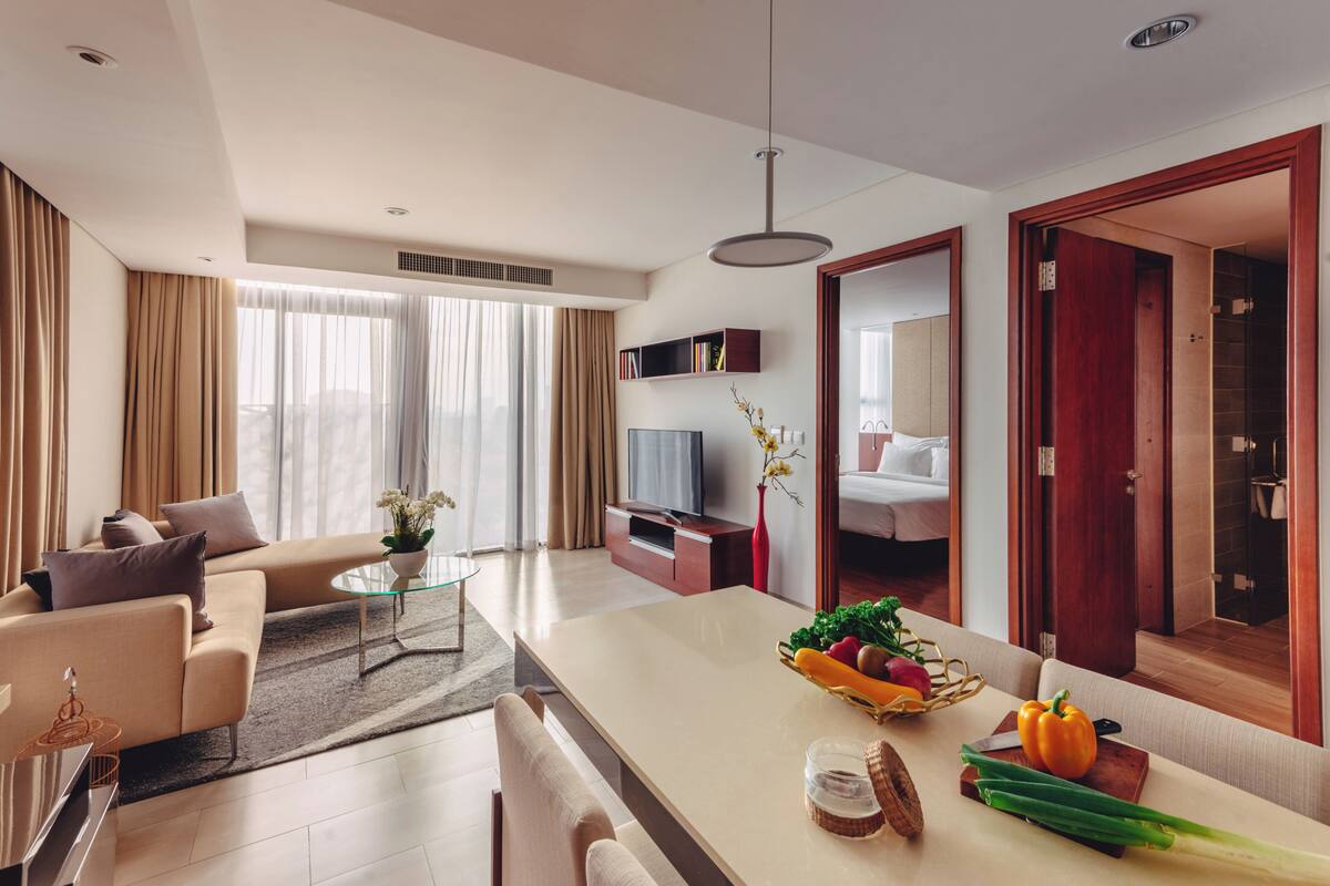 Een moderne hotelkamer met een bank, televisie, eethoek en een grote spiegel.