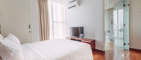 Una camera d'albergo con un letto, una televisione, una scrivania e un box doccia in vetro.