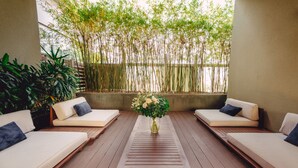 A modern outdoor seating area with two sofas, a wooden table, and a vase of flowers. - SILA Urban Living (Ho Chi Minh City)