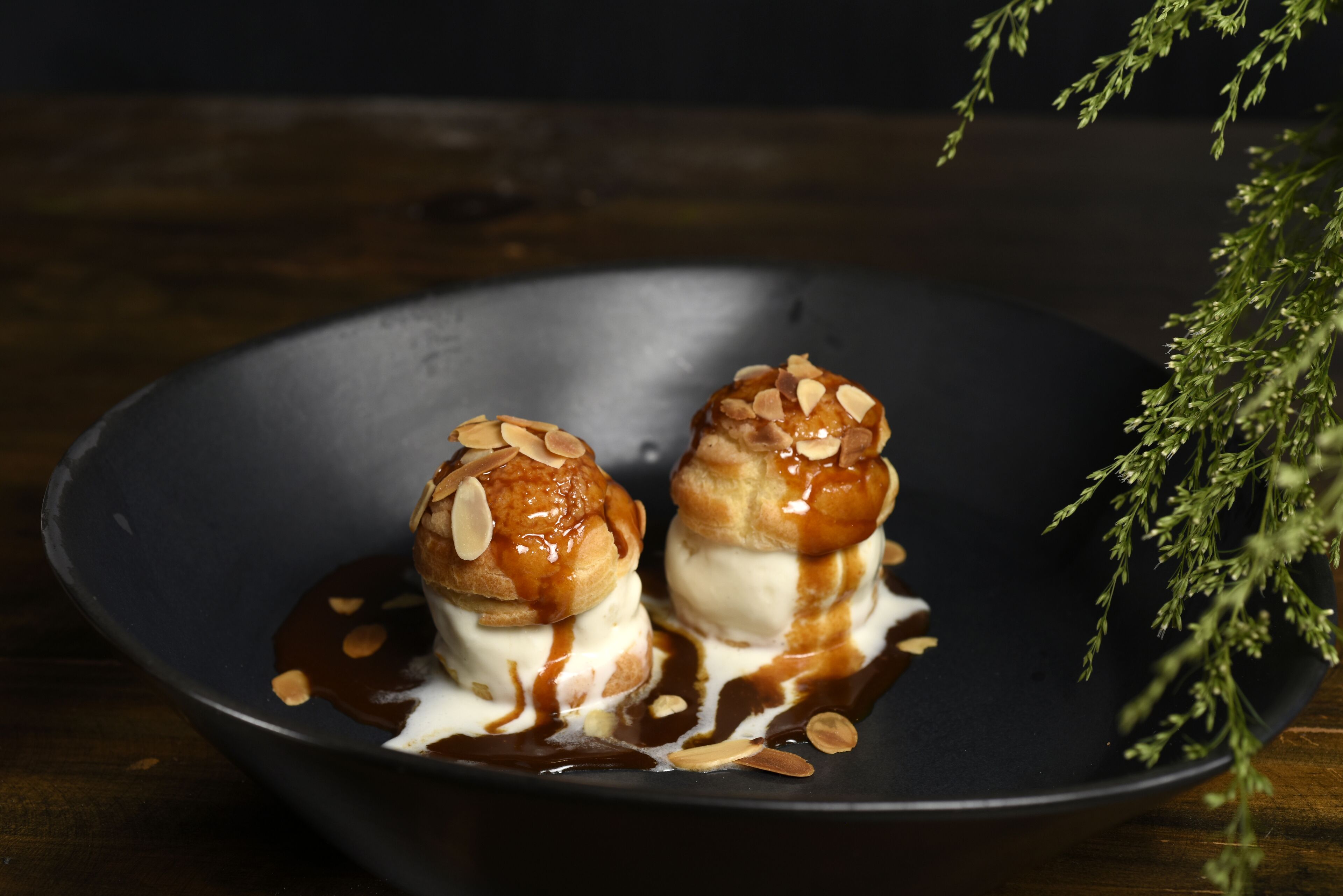 Two desserts on a dark plate with a dark background.