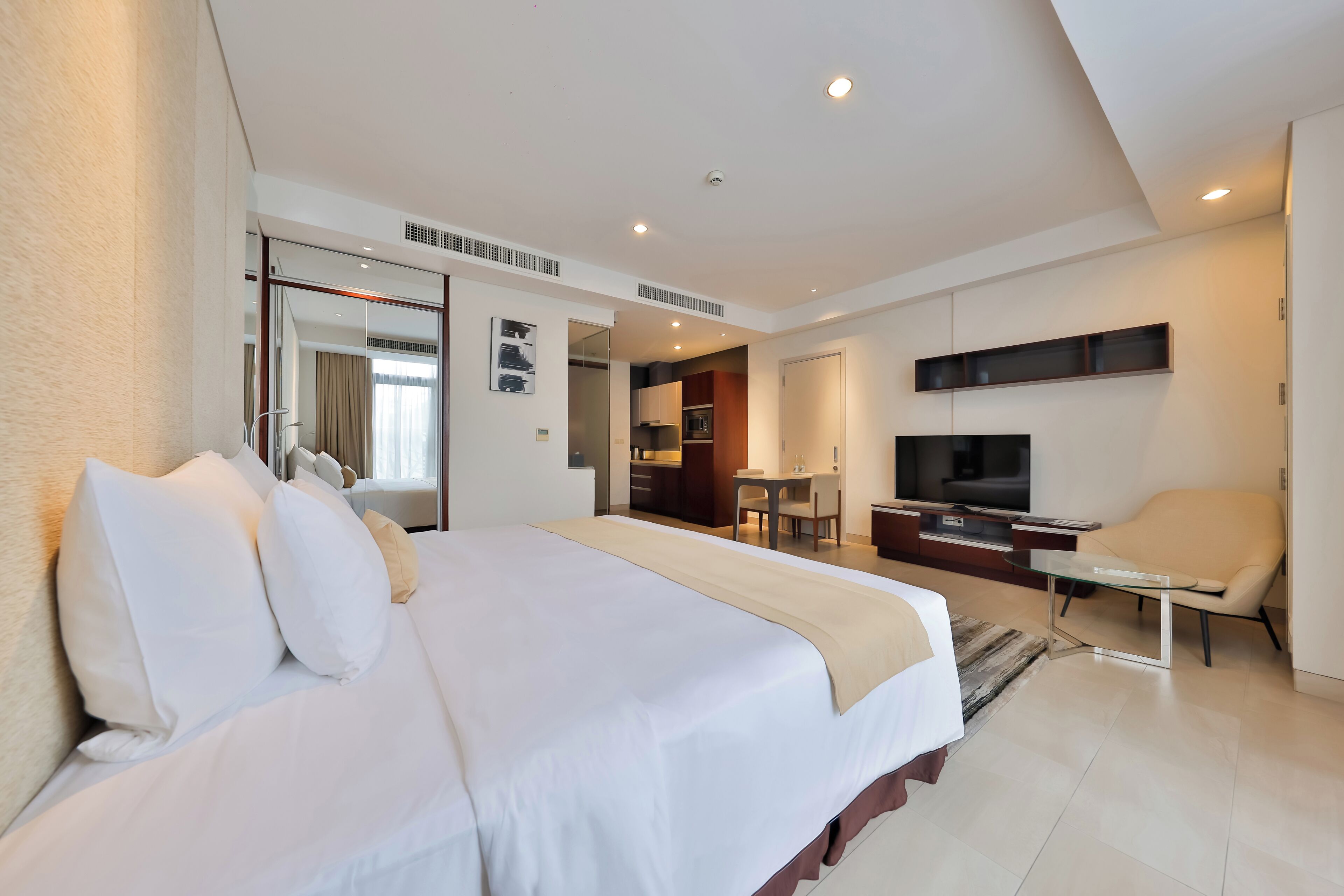 A hotel room with a large bed, a TV, a desk, and a chair.