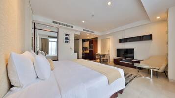 A hotel room with a large bed, a TV, a desk, and a chair.