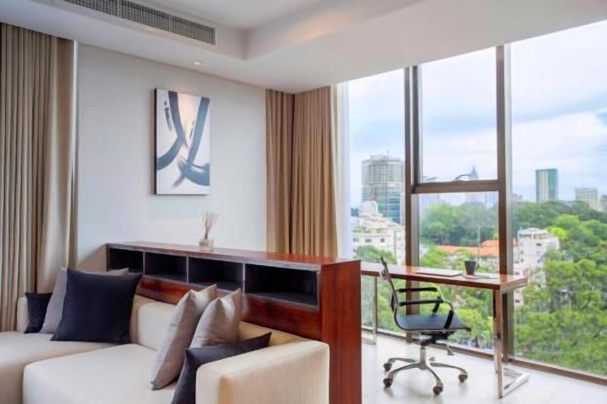 Una habitación de hotel moderna con un ventanal grande, un sofá, un escritorio y vistas a la ciudad.