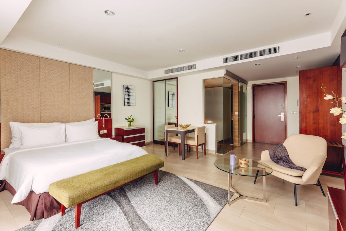 Een moderne hotelkamer met een groot bed, een bureau, een stoel en een glazen salontafel.