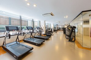 Une salle de sport équipée de tapis de course, de vélos elliptiques et d'appareils de musculation.
