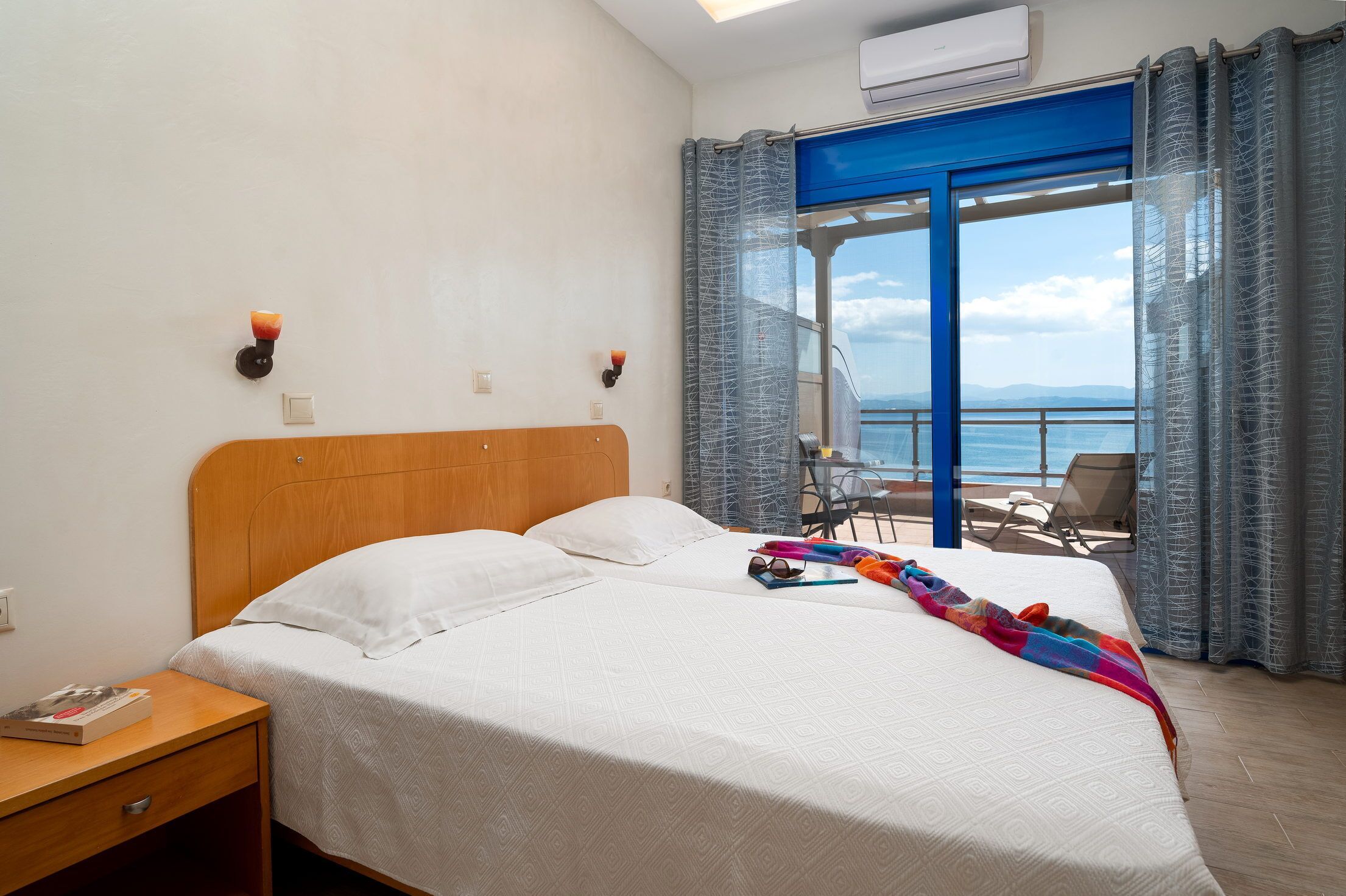 Une chambre d’hôtel comprenant un lit, une table de chevet, une table avec une chaise et un balcon avec vue sur la mer.