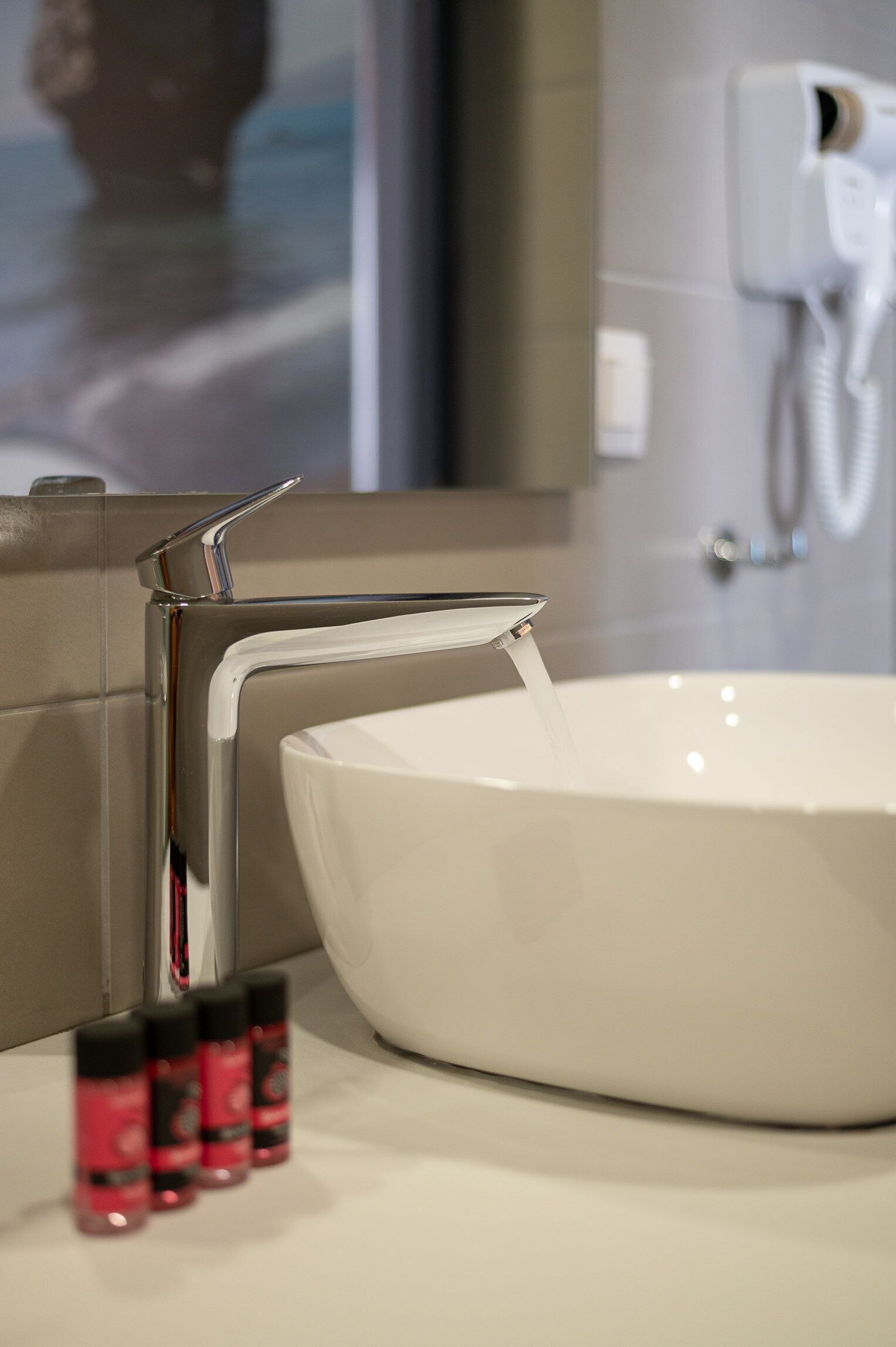 Un baño moderno con un grifo cromado, un lavamanos blanco y un cabezal de ducha de mano.