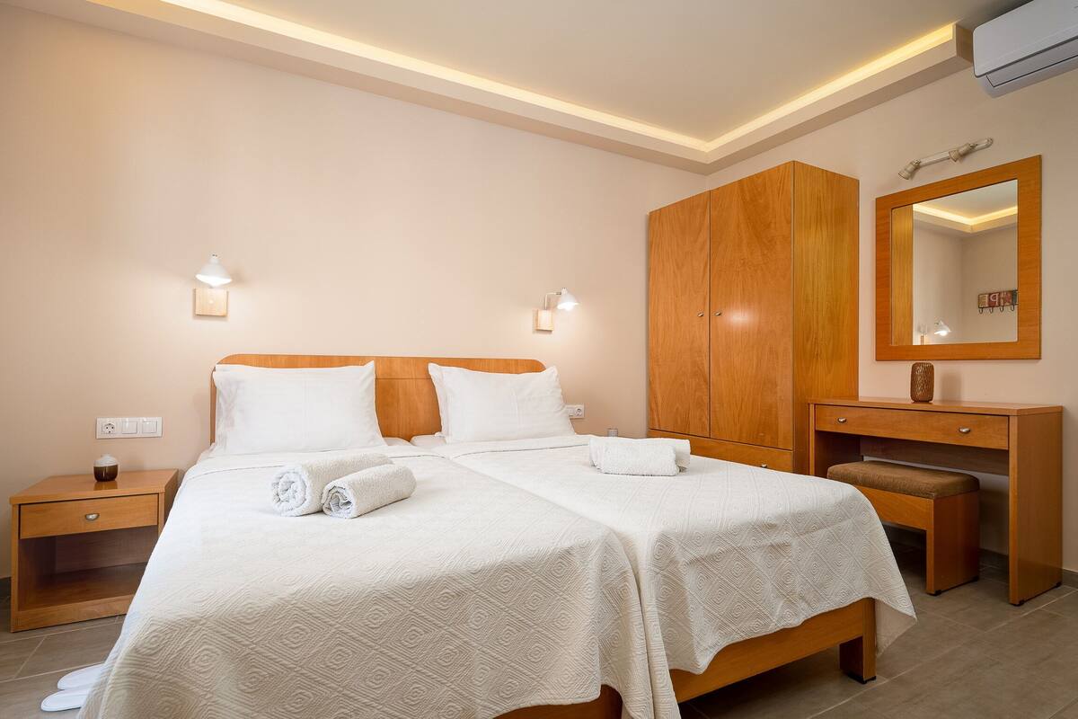 A hotel room with a large bed, wooden wardrobe, bedside tables, and a mirror.