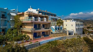 A coastal building with multiple balconies, a staircase, and a view of the sea. - Minos Boutique Hotel Agia Galini (Agios Vasileios)