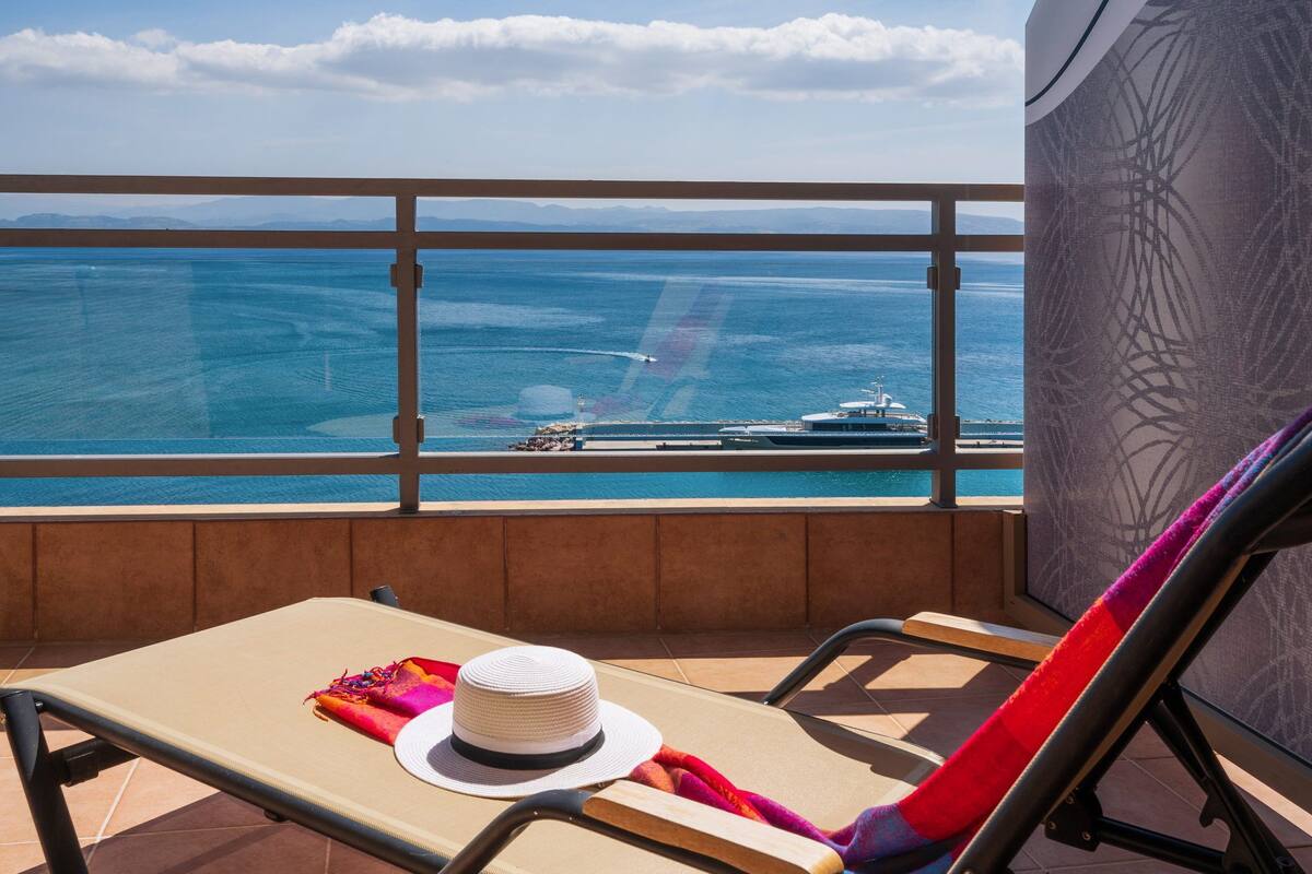 A balcony with a view of the sea and a yacht.