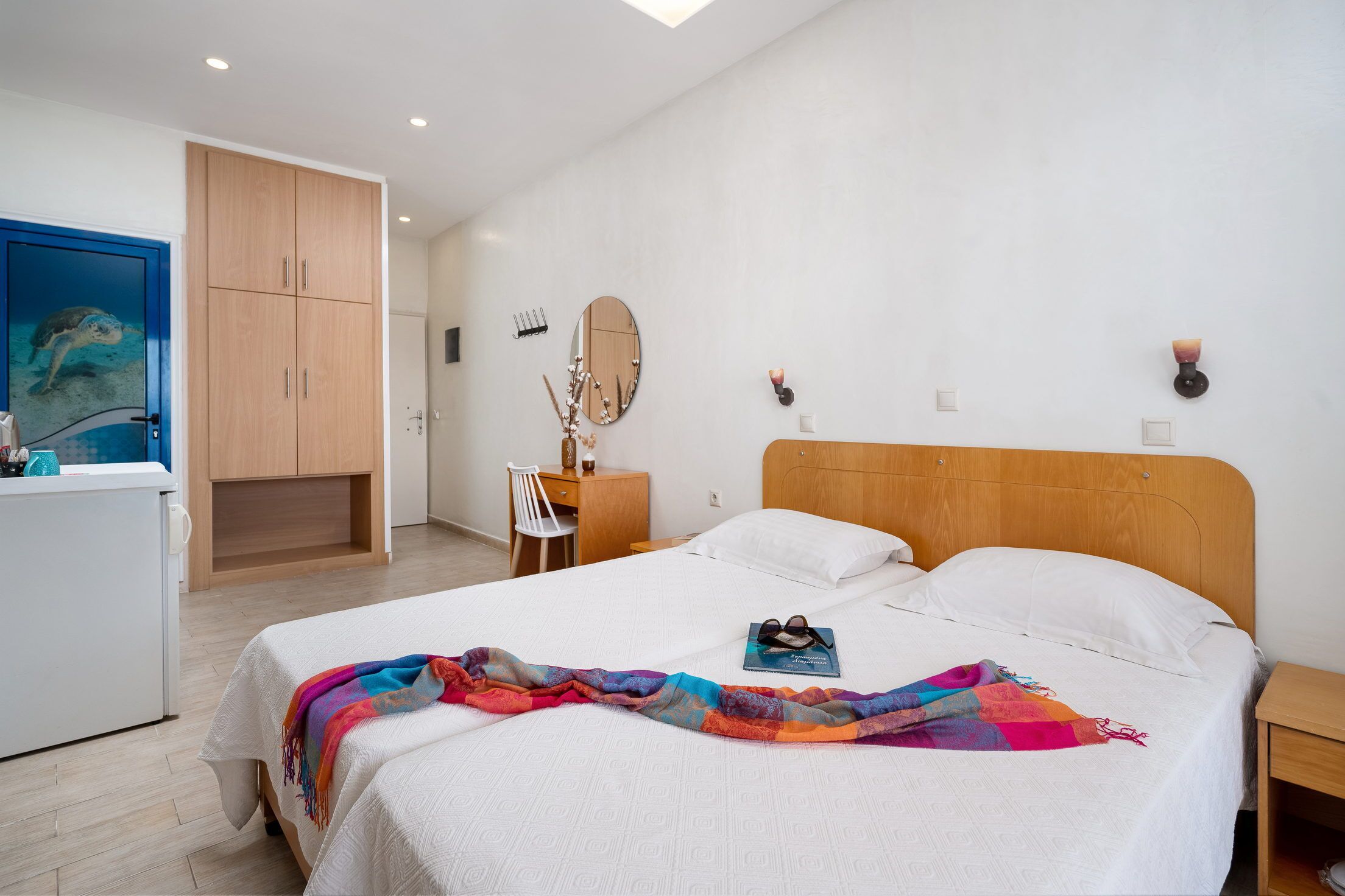 A bedroom with a bed, a dresser, a mirror, and a desk.