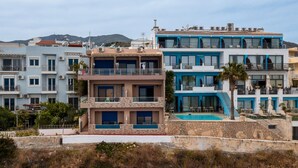 A multi-story hotel with balconies, a swimming pool, and a view of the mountains. - Minos Boutique Hotel Agia Galini (Agios Vasileios)
