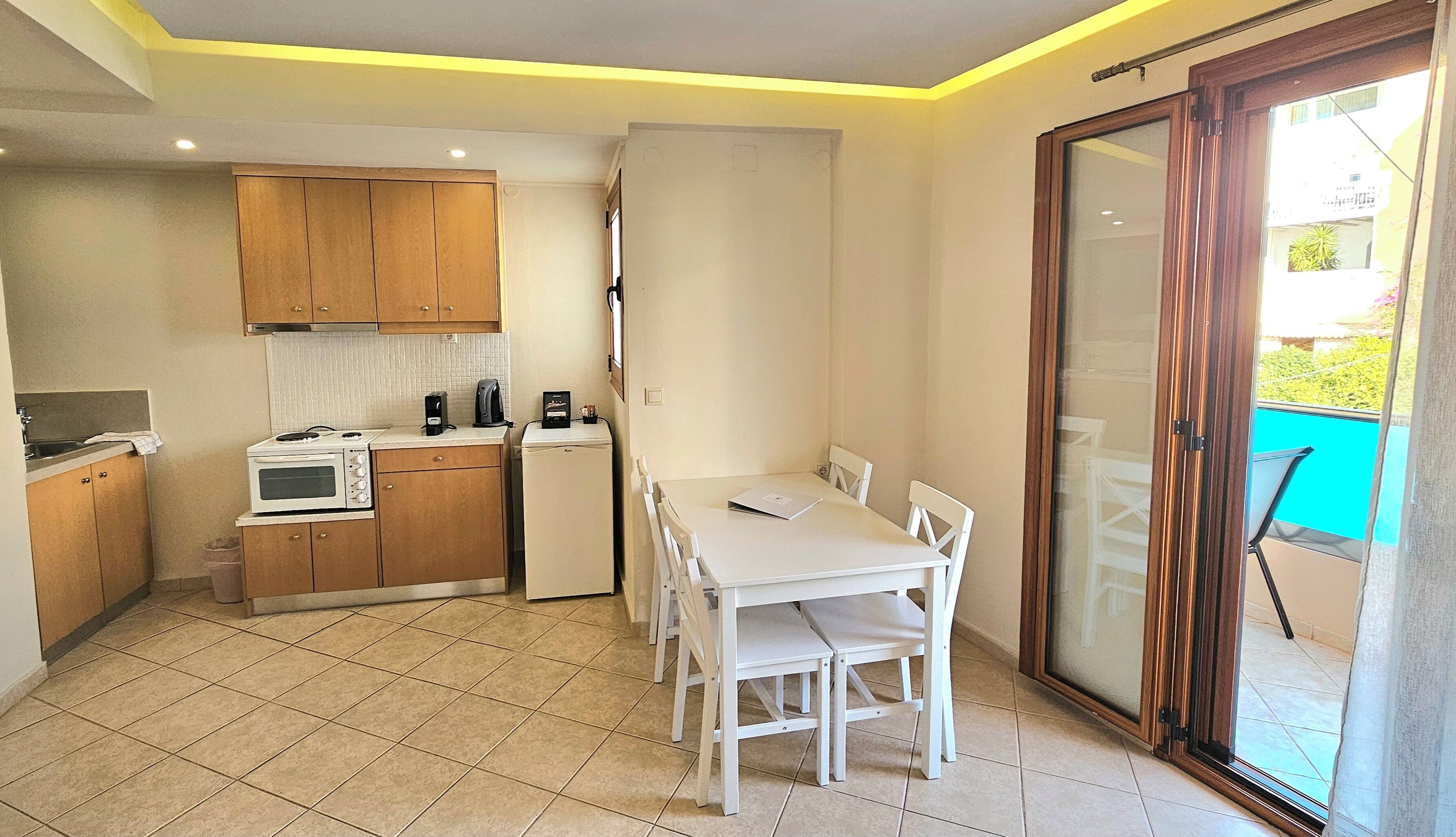 Una cocina compacta con comedor, puerta corrediza de vidrio a un espacio exterior y un refrigerador pequeño.
