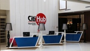 A reception area with a 'CitiHub' sign, two reception desks, and two lamps. - Citihub Hotel @Kediri (Kediri)