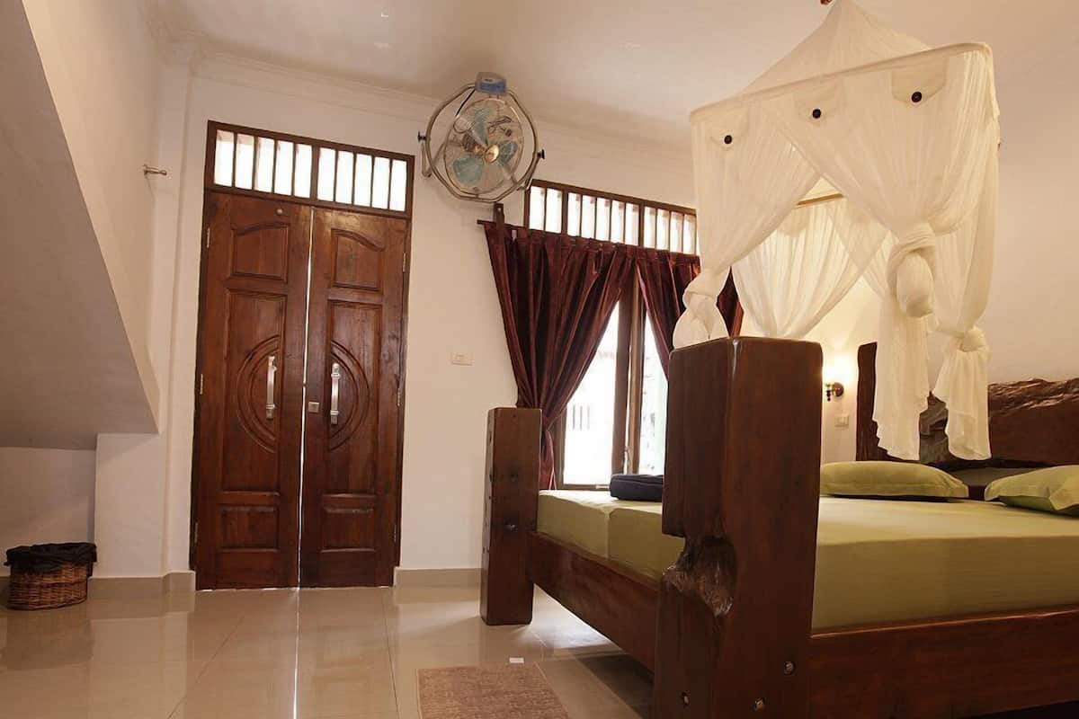 A bedroom with a wooden bed, a ceiling fan, and a large window with curtains.