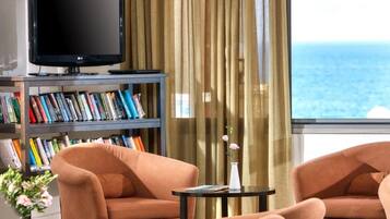 Una sala de estar con televisor, estanterías, dos sofás, una mesita y vista al océano.