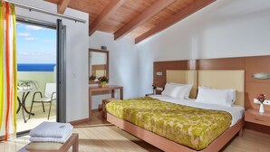 A bedroom with a bed, bedside table, and a desk with a chair. - Panormo Beach (Mylopotamos)
