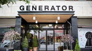The entrance to a hotel named GENERATOR with a modern design, featuring a wooden canopy and large potted plants. - Generator Stockholm (Stockholm)