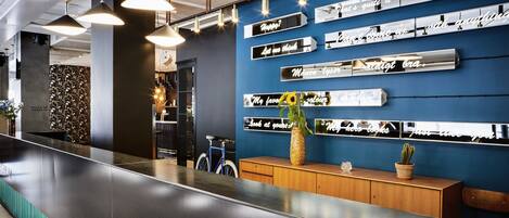 A modern reception area with a long counter, pendant lighting, and a wall with motivational quotes.
