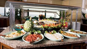 Buffet com diversos pratos e uma vitrine de vidro.