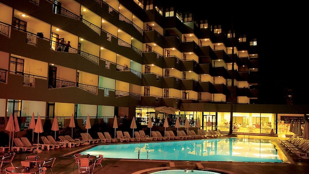 Um hotel com piscina, espreguiçadeiras e guarda-sóis.