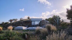 A modern house with a stone facade, a glass entrance, and a patio area with outdoor seating.