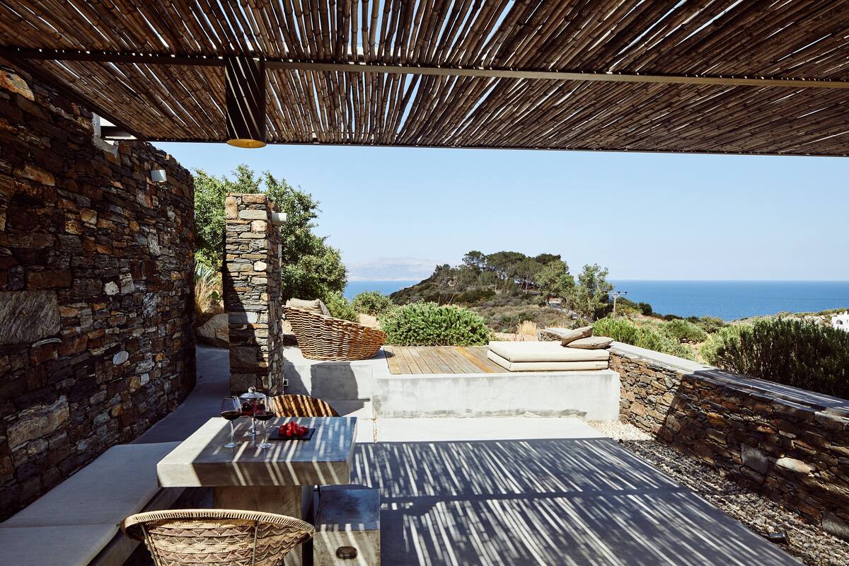 A stone-walled outdoor seating area with a view of the sea.