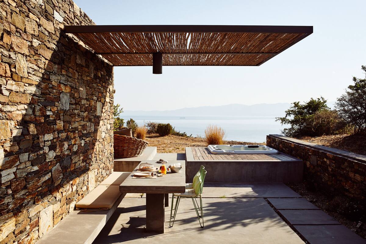 A stone wall, outdoor seating, a hot tub, and a view of the ocean.
