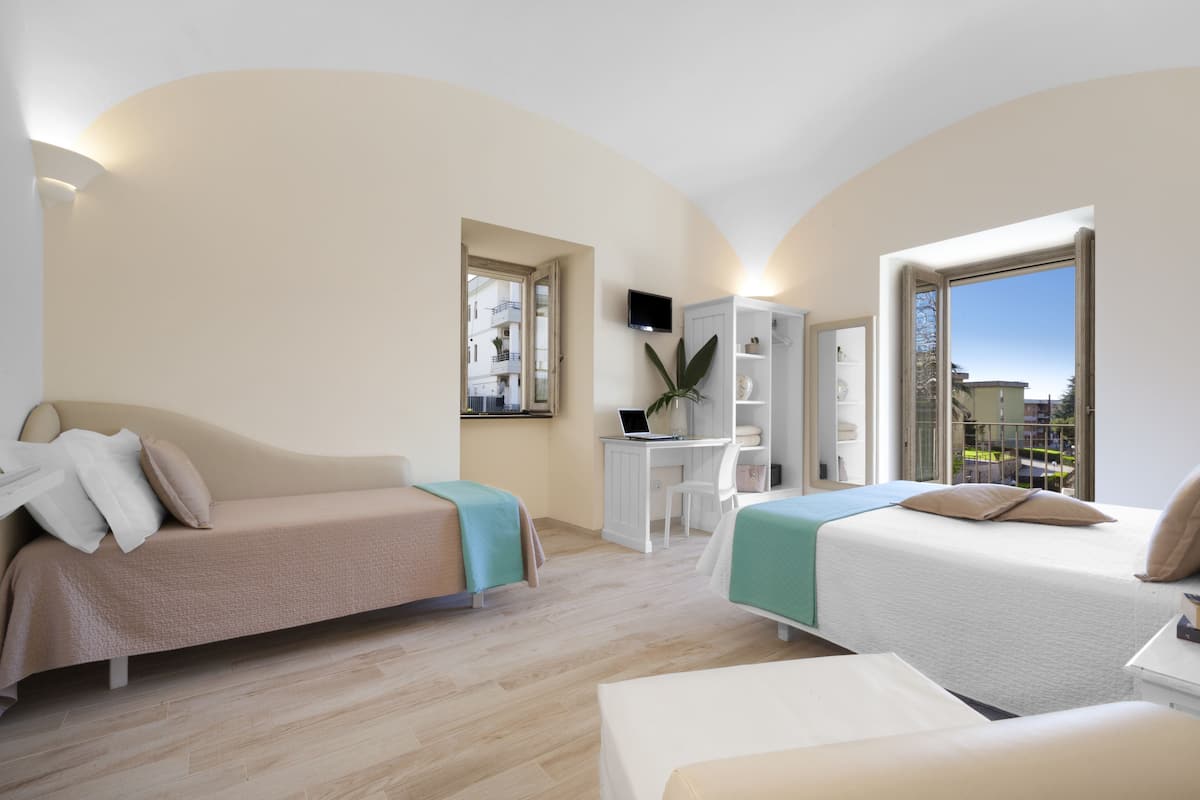 Ein modernes Hotelzimmer mit einer Couch, einem Bett, einem Schreibtisch und Blick auf die Stadt.