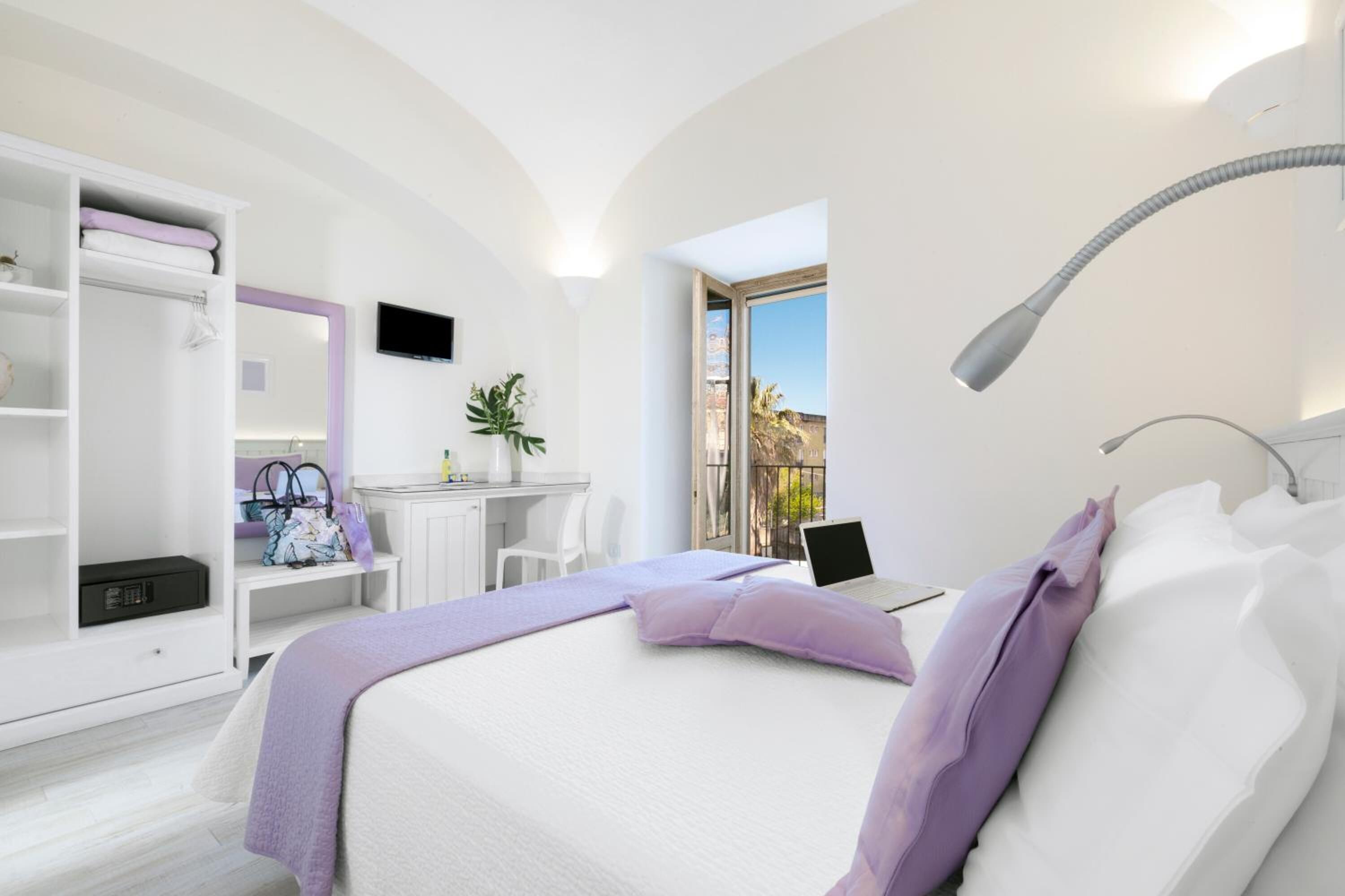 A modern bedroom with a bed, a desk, and a laptop.