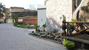 Un quartier résidentiel avec une allée pavée, un mur en pierre et un petit jardin agrémenté de diverses plantes et fleurs.