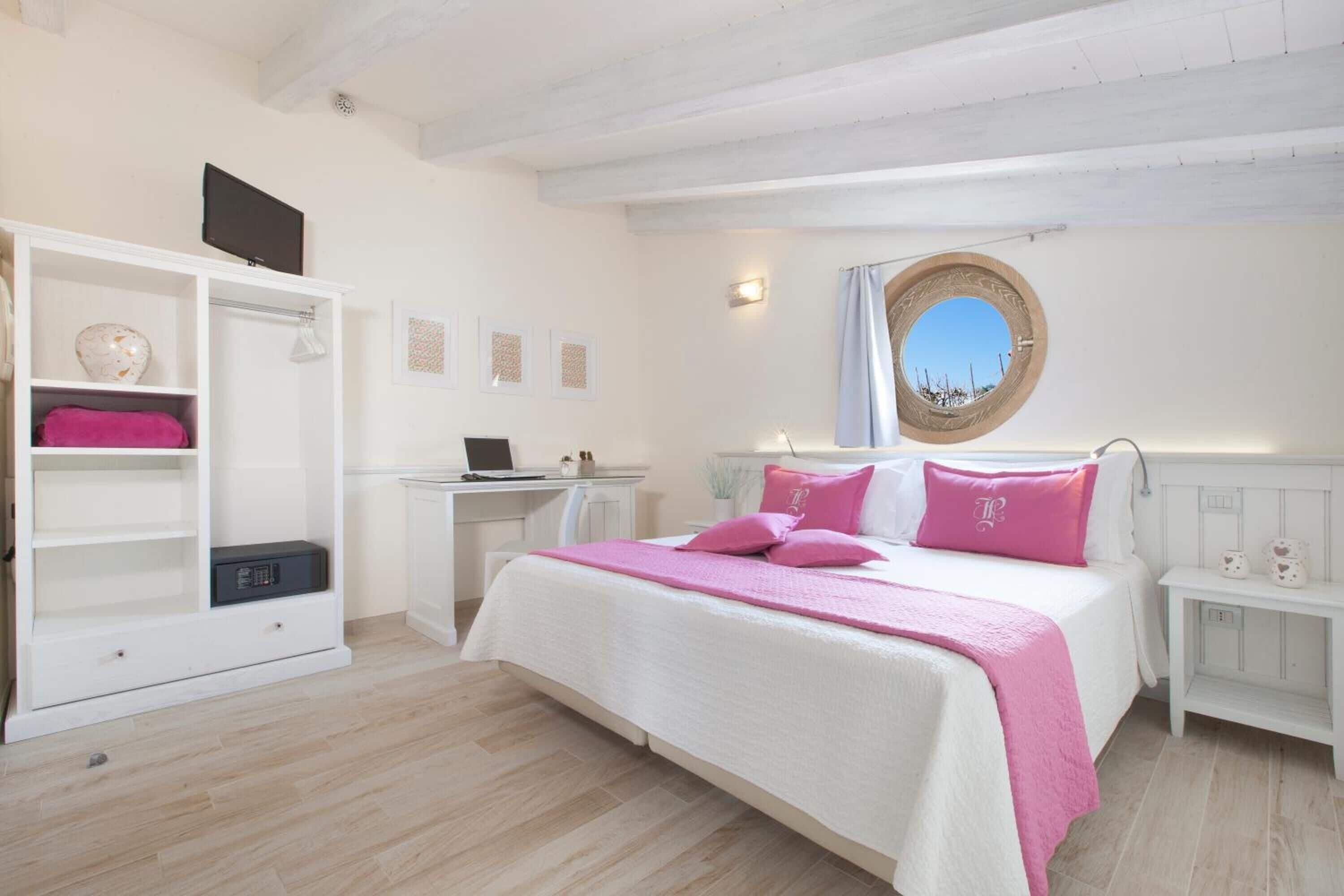 A bedroom with a bed, a desk, a wardrobe, and a mirror.