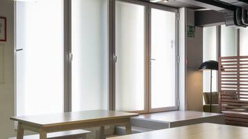 Un interior moderno con amplios ventanales, varias mesas e iluminación colgante.