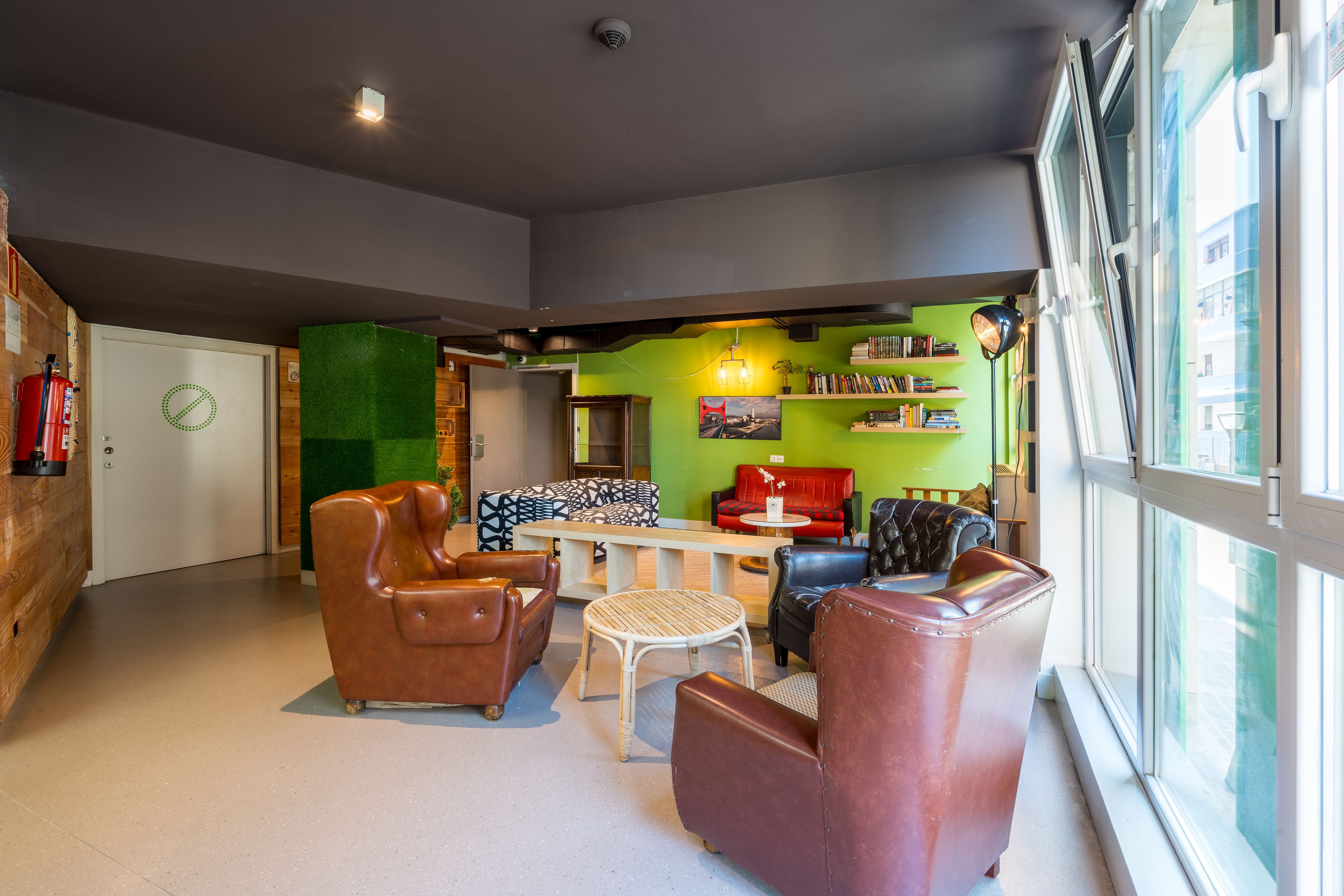 Un espacio lounge moderno con sofás de cuero, una mesa redonda y una estantería.